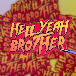 May include: A sticker with the text "HELL YEAH BROTHER" in a bold, stylized font. The text is primarily orange and yellow, outlined in black, set against a red background. Other stickers with the same design are visible.