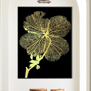 Puede incluir: Un diseño de flor de hibisco de hoja de oro sobre un fondo negro. El diseño está enmarcado y colgado en una pared blanca en un pasillo.