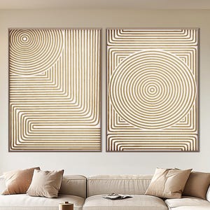 Può includere: Un soggiorno moderno con un divano angolare beige, un tavolino rotondo scuro e due opere d'arte astratte da parete con disegni a linee concentriche. La stanza ha una palette di colori neutri, un tappeto e un pouf marrone.