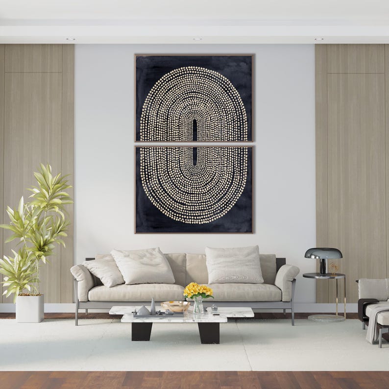 May include: Two-piece abstract wall art featuring a dark blue background with a cream-colored dotted design. The artwork is displayed above a light-colored sofa in a modern living room setting. The room includes a white rug, a coffee table, and a potted plant.