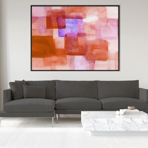 Peut inclure: Peinture abstraite &agrave; l'aquarelle dans un cadre noir. L'&oelig;uvre pr&eacute;sente des formes rectangulaires superpos&eacute;es dans des tons orange, rouge, violet et rose. La peinture est expos&eacute;e au-dessus d'un canap&eacute; d'angle gris et d'une table basse en marbre blanc.