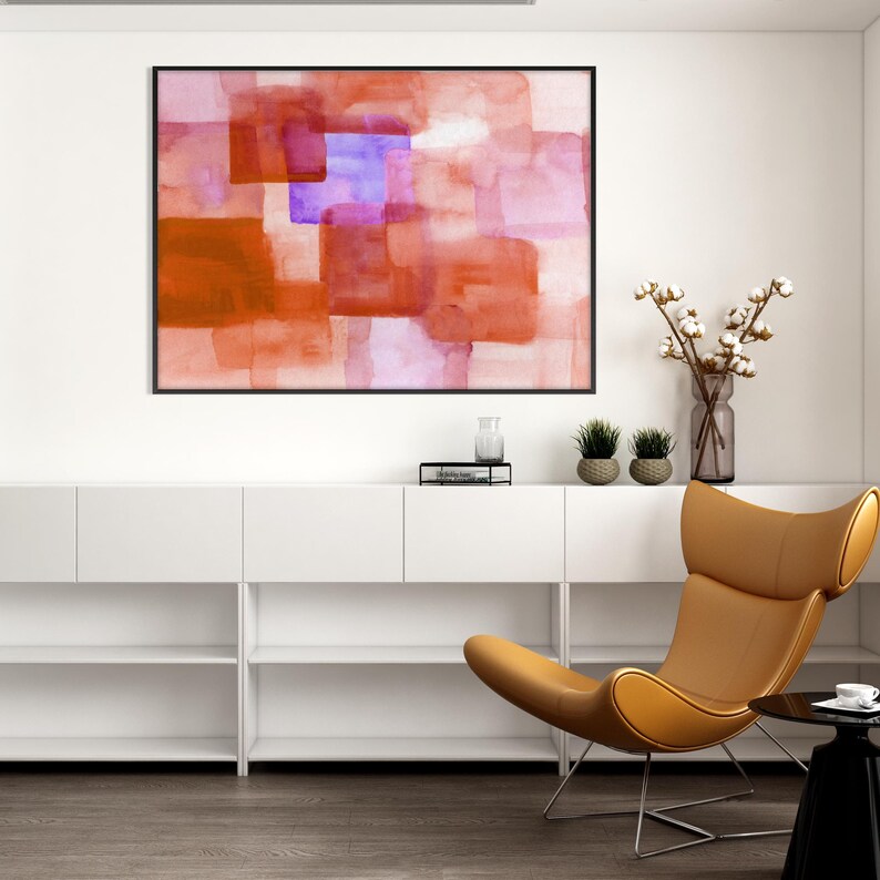 Peut inclure: Peinture abstraite &agrave; l'aquarelle dans un cadre noir. L'&oelig;uvre pr&eacute;sente des formes rectangulaires superpos&eacute;es dans des tons orange, rouge et violet. Int&eacute;rieur moderne et minimaliste avec une chaise en cuir beige et un meuble de rangement blanc.
