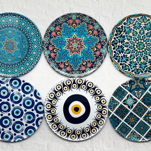 Può includere: Sei piatti decorativi in ceramica con motivi blu e bianchi. I piatti presentano diversi disegni, tra cui forme geometriche, motivi floreali e il simbolo del malocchio.