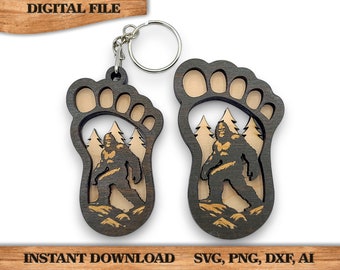 May include: A wooden keychain featuring a Bigfoot silhouette inside a footprint. The keychain is brown with a light brown interior and a silver key ring.