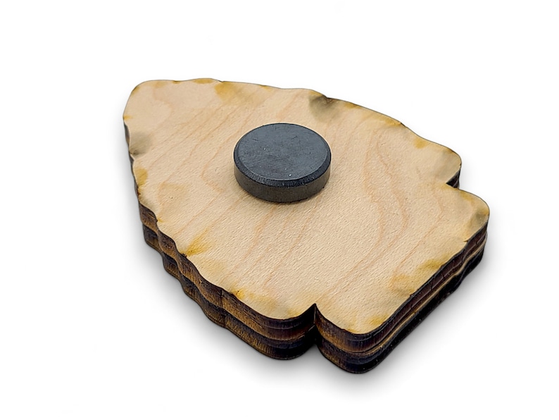 May include: A wooden cutout of a tree with a black magnet on the back. The tree is made of multiple layers of wood and has a rough, natural edge.