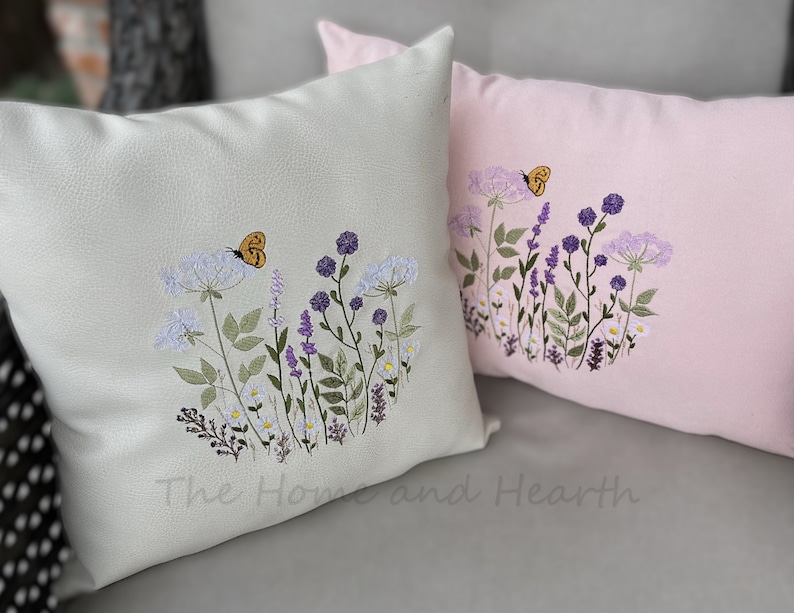 Pode incluir: Duas almofadas bordadas com um design floral. A almofada &agrave; esquerda &eacute; verde claro com uma borboleta amarela. A almofada &agrave; direita &eacute; rosa com uma borboleta amarela.