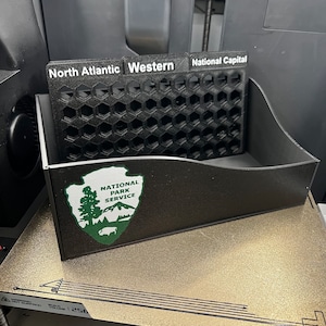 May include: A black plastic organizer with three compartments labeled "North Atlantic", "Western", and "National Capital". The organizer has a honeycomb design and features the National Park Service logo.