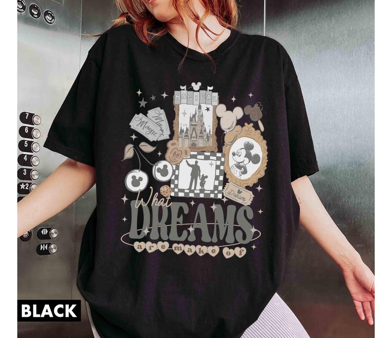 K&ouml;nnte beinhalten: Schwarzes T-Shirt mit einem Disney-Motiv. Das Design zeigt Mickey Mouse, ein Schloss und den Text "What Dreams are Made Of". Das T-Shirt hat einen Rundhalsausschnitt und kurze &Auml;rmel. Der Text "BLACK" steht unten.