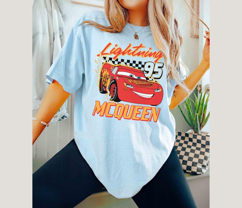 Peut inclure: Un t-shirt bleu clair avec un imprim&eacute; de Flash McQueen du film Cars de Disney Pixar. L'imprim&eacute; comprend le texte "Lightning McQueen 95".