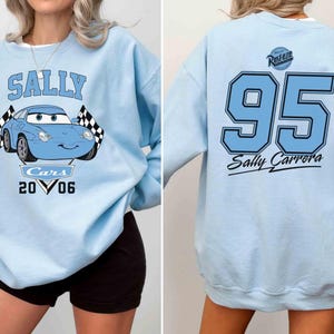 Pu&ograve; includere: Felpa blu chiaro con un'immagine di cartone animato di Sally del film Cars. La felpa ha il testo "Sally" e "Cars 2006" stampato sul davanti. La parte posteriore della felpa ha il numero "95" e il testo "Sally Carrera" stampato su di essa.