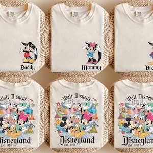 以下が含まれることがあります： ディズニーのキャラクターのグラフィックがプリントされたクリーム色のTシャツ6枚セット。Tシャツには、ミッキーマウス、ミニーマウス、ドナルドダック、そしてディズニーランドパークのシーンの前にいるディズニーキャラクターのグループが描かれています。Tシャツには、「パパ」、「ママ」、「ブラザー」、「ウォルトディズニーのディズニーランドEst. 1955」という文字がプリントされています。
