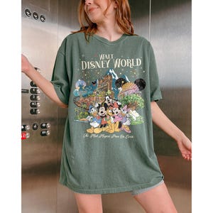 May include: Green t-shirt featuring a Disney World graphic with Mickey Mouse, Donald Duck, and other characters. The text "Walt Disney World" and "The Most Magical Place On Earth" are printed on the shirt, creating a nostalgic design.