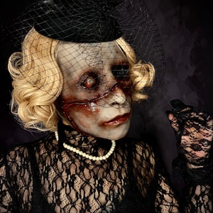 May include: A woman wearing a black lace dress and a black hat with a veil. Her face is covered in white and red makeup, creating a spooky and eerie look.