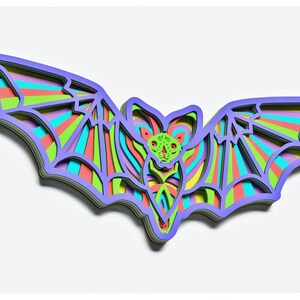 May include: A colourful layered paper bat with a rainbow striped design. The bat is cut out of paper and has a 3D effect.