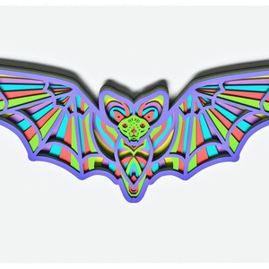 May include: A colourful paper bat with layered wings and a detailed face. The bat is made of paper and has a layered design with shades of green, blue, pink, and purple.