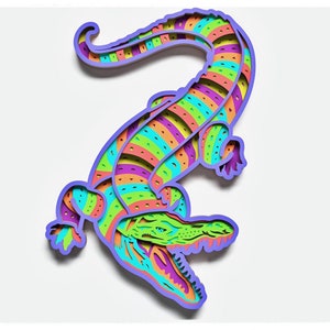 May include: A colorful paper cut-out of an alligator with a striped pattern in shades of green, orange, purple, and blue. The alligator is standing on its hind legs with its mouth open.