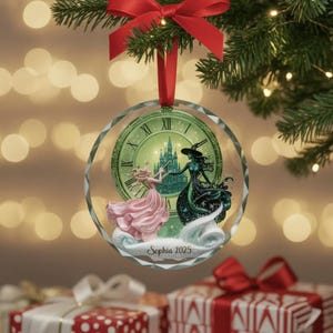 Peut inclure: Une boule de Noël ronde et transparente avec un motif de cadran d'horloge vert représentant deux personnages et un château. L'ornement est orné d'un ruban rouge et du texte "Sophia 2025".