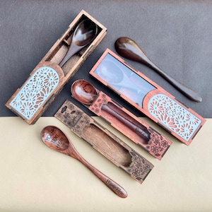 Könnte beinhalten: Vier Holzlöffel in dekorativen Boxen. Die Boxen sind aus Holz und haben ein Blumenmuster. Die Löffel sind aus dunklem Holz und haben eine glatte Oberfläche. Ein Löffel hat den Text "Your Text Here" eingraviert. Ein weiterer Löffel hat den Text "Best Dad" eingraviert. Der dritte Löffel hat den Text "Name Here" eingraviert.