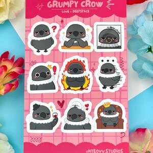 May include: Sheet of stickers featuring a cartoon crow with various expressions. The crow is primarily gray with a white ruffled collar. The stickers have text that reads "GRUMPY CROW LOVE & DEEPSPACE" and "u doin what". The background is pink.
