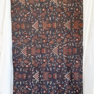 Könnte beinhalten: Ein dunkelbrauner und weißer Stoff mit einem sich wiederholenden Muster aus stilisierten Vögeln und Blumen. Der Stoff hat einen dezenten Glanz und eine weiche Textur.