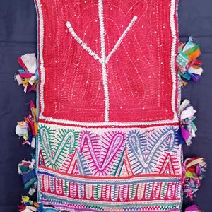 Può includere: Un tessuto vibrante, fatto a mano, con sfondo rosso e intricate cuciture bianche. Il design presenta un motivo centrale e bordi colorati e fantasia. Impreziosito da nappe di tessuto colorato lungo i bordi, questo pezzo mette in mostra l'artigianato tradizionale.