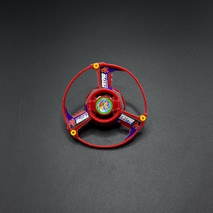 May include: Red and purple plastic toy top with a red scorpion design and the word "TRYPIO" printed on it.