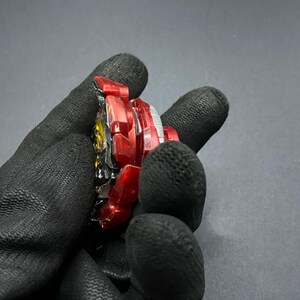 K&ouml;nnte beinhalten: Ein rotes und schwarzes Kreiselspielzeug mit einer durchsichtigen Plastikscheibe und einer Metallbasis.