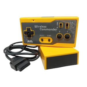 May include: A yellow Wireless Commander video game controller with a black directional pad, two round black buttons labeled A and B, and two smaller buttons labeled SELECT and START. It includes a black cable with a rectangular connector plug.