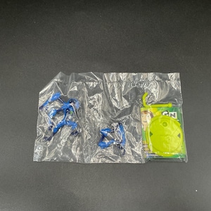 May include: A sealed plastic package containing two blue action figures and a green and yellow card with the text "CN" and "FIGURE". The figures are in various action poses.