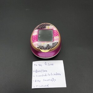 Puede incluir: Un juego electr&oacute;nico port&aacute;til rosa y dorado con pantalla. La secci&oacute;n superior presenta un patr&oacute;n floral y de lunares. El dispositivo tiene tres botones debajo de la pantalla. Hay una nota manuscrita al lado del dispositivo.