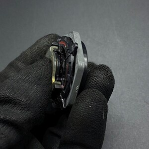K&ouml;nnte beinhalten: Nahaufnahme eines silbernen und schwarzen Autoteils mit einem roten und schwarzen Ring. Das Teil hat eine strukturierte Oberfl&auml;che und scheint aus Metall zu sein.