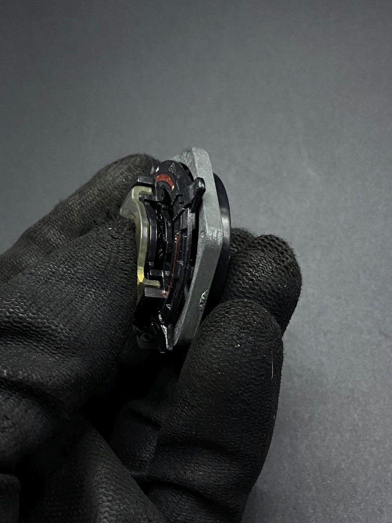 K&ouml;nnte beinhalten: Nahaufnahme eines silbernen und schwarzen Autoteils mit einem roten und schwarzen Ring. Das Teil hat eine strukturierte Oberfl&auml;che und scheint aus Metall zu sein.