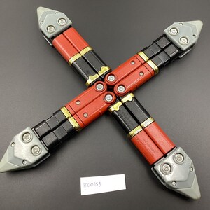 May include: Four black and red folding knives with gray handles and silver accents. The knives are arranged in a cross shape.