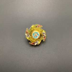 May include: A yellow and red plastic spinning top with a blue and gold centre. The top has a star-shaped design and is a popular toy for children.