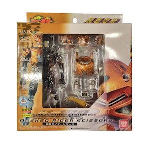 May include: A Bandai Soucharu Henshin Series Masked Rider Scissor action figure in its original packaging. The box features a clear plastic window displaying the figure, orange armour pieces, and accessories. Text includes Masked Rider Scissor.
