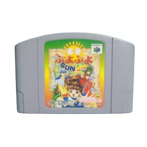 Puede incluir: Un cartucho de videojuego gris para Nintendo 64 con una etiqueta colorida de Puyo Puyo Sun 64. La etiqueta muestra un gran sol amarillo, personajes de estilo anime y el texto Puyo Puyo Sun 64, NUS-NPYJ-JPN y Compile 1997.