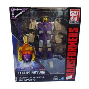May include: A Transformers Generations Titans Return Decepticon Hazard and Blitzwing action figure in its original packaging. The box features a purple and tan robot, a yellow helmet graphic, and the text Titans Return and Transformers.