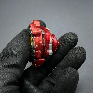 K&ouml;nnte beinhalten: Rotes und silbernes Kreiselspielzeug mit einer durchsichtigen Plastikspitze. Der Kreisel befindet sich in einer Hand, aber die Hand ist nicht sichtbar.