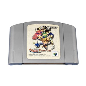 Puede incluir: Un cartucho de videojuego gris para Nintendo 64 con una etiqueta que muestra personajes coloridos de estilo anime, el logotipo de Nintendo y texto en japonés que incluye Shiren 2. La etiqueta también muestra 2000 CHUN SOFT, MADE IN JAPAN, NUS-NSIJ-JPN.