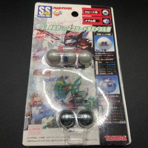 Puede incluir: Un paquete de canicas Strike Shot 91 para un juego. El paquete presenta un robot de dibujos animados y el texto "91 必殺球 VOL.2 スピード弾&メタル弾". El paquete incluye tres canicas plateadas y dos canicas negras.