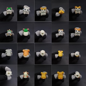 May include: A collection of small, colorful hamster figurines. Each figurine is uniquely designed with different colors and accessories, such as hats and bows. The hamsters are in various poses, showcasing their playful and cute appearance. The background is a solid dark gray.