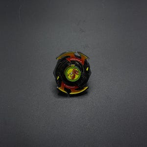 Könnte beinhalten: Schwarz-gelber Beyblade mit rotem und gelbem Design. Der Beyblade trägt den Text "DRIVIZER-S".