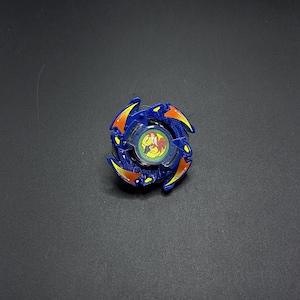 May include: A blue and orange Beyblade with a yellow and red design. The Beyblade has a green center with a red and yellow dragon design.