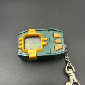 May include: A set of three ceramic mugs with a speckled, cream-colored glaze. Each mug features a different hand-painted design: a blue and green leaf, a yellow flower, and a red berry. The mugs have a simple, modern design.