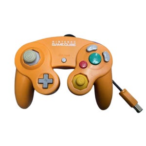 Könnte beinhalten: Ein orangefarbener Nintendo GameCube Videospiel-Controller mit einer zentralen Start/Pause-Taste, einem grauen Steuerkreuz, einem grünen A-Knopf, einem roten B-Knopf, grauen X- und Y-Tasten, einem gelben C-Stick, einem grauen Analogstick und einem Kabel.