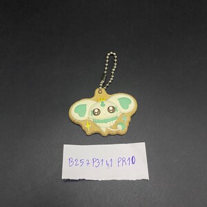 K&ouml;nnte beinhalten: Ein Schl&uuml;sselanh&auml;nger mit einem Cartoon-Charakter, der ein hellbraunes, keksartiges Design, mintgr&uuml;ne Akzente und eine silberne Kette aufweist. Der Charakter hat gro&szlig;e Augen und Sterndetails. Ein wei&szlig;es Etikett darunter lautet "B257 P3161 PR10".