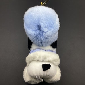 May include: A white plush dog wearing a blue fur hat and a white fur coat. The dog has black eyes and a black nose.