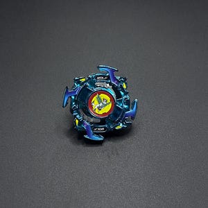Könnte beinhalten: Ein blaues und violettes Beyblade mit einem Wolf-Design und dem Wort "WOLF" darauf gedruckt.