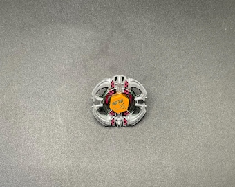 Könnte beinhalten: Ein silber-rotes kreisförmiges Objekt mit dem Text "SGTD" in Gold auf einem gelb-roten Hintergrund. Das Objekt hat ein komplexes Design mit mehreren Schichten und kleinen roten Akzenten.