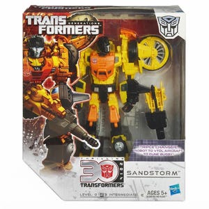 May include: A Transformers Generations Sandstorm action figure in its original packaging. The yellow and orange robot is visible through the clear plastic window. The box features the text Thrilling 30, Triple Changer, and Robot to VTOL Aircraft to Dune Buggy.